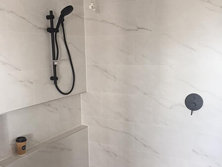 Walk-in shower with marble-look tiles and matte black tapware