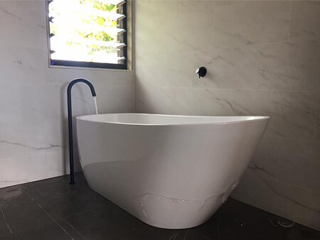 Freestanding bath with floor-mounted matte black spout after fit-off