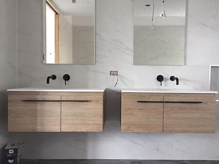 Double floating vanity with matte black wall mixers during bathroom fit-off